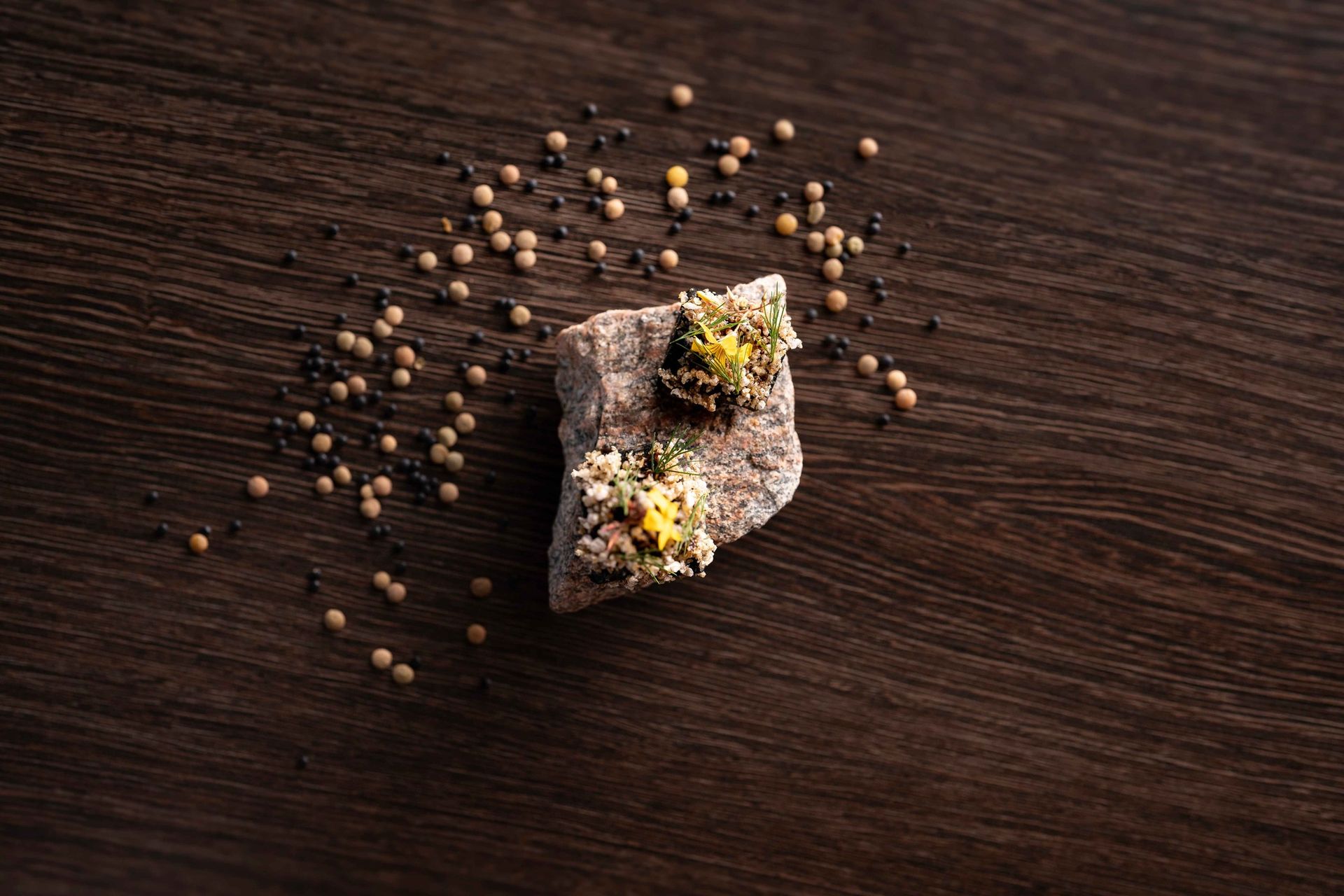 A piece of food is sitting on top of a wooden table surrounded by peppercorns.
