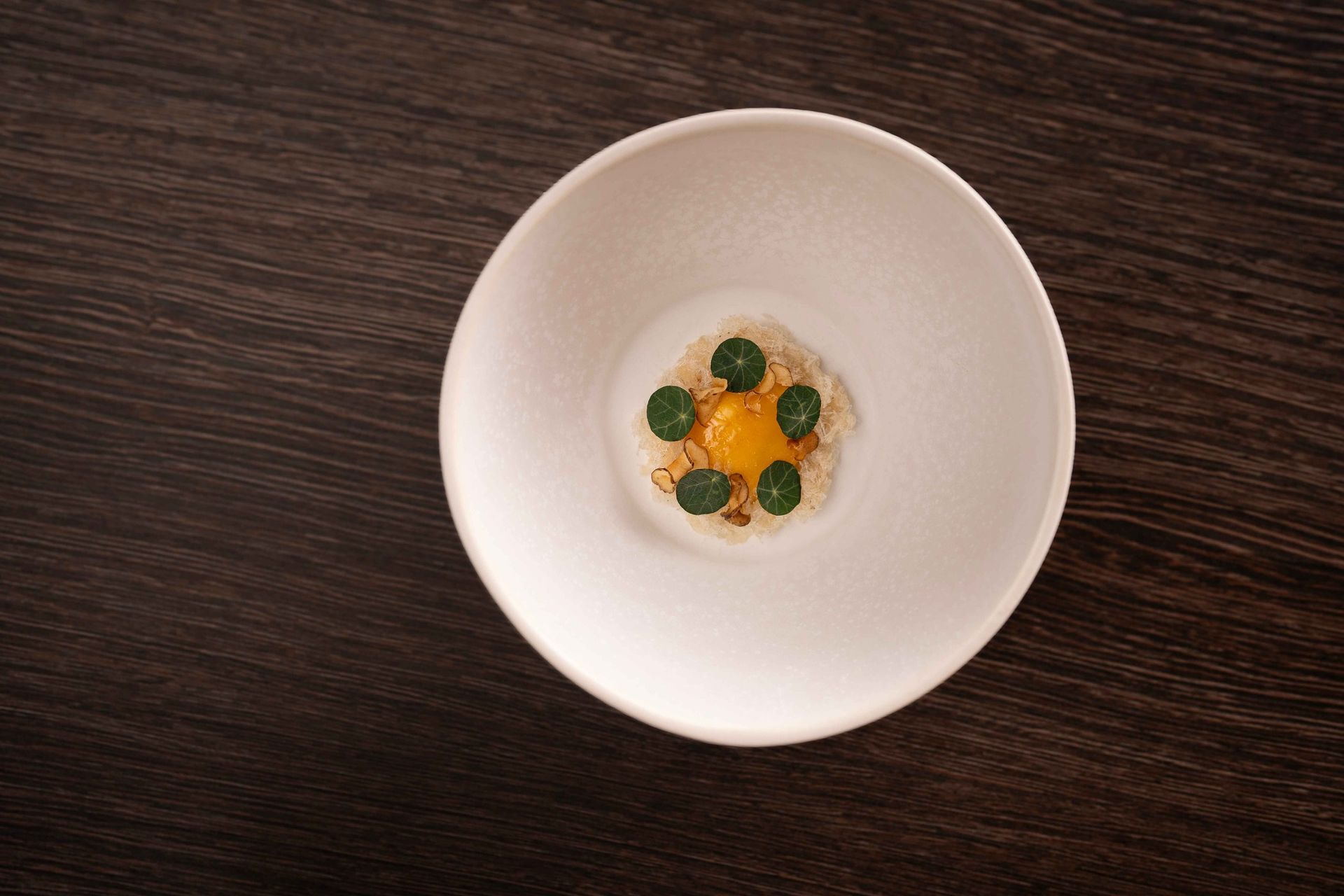 A white bowl filled with food on a wooden table.