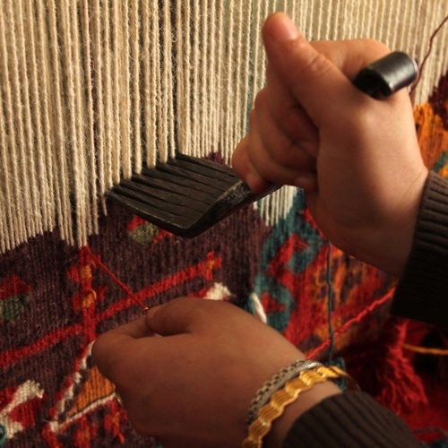 Rug weaving - Close-up of a woman hand-weaving a colorful rug in Carlsbad, CA