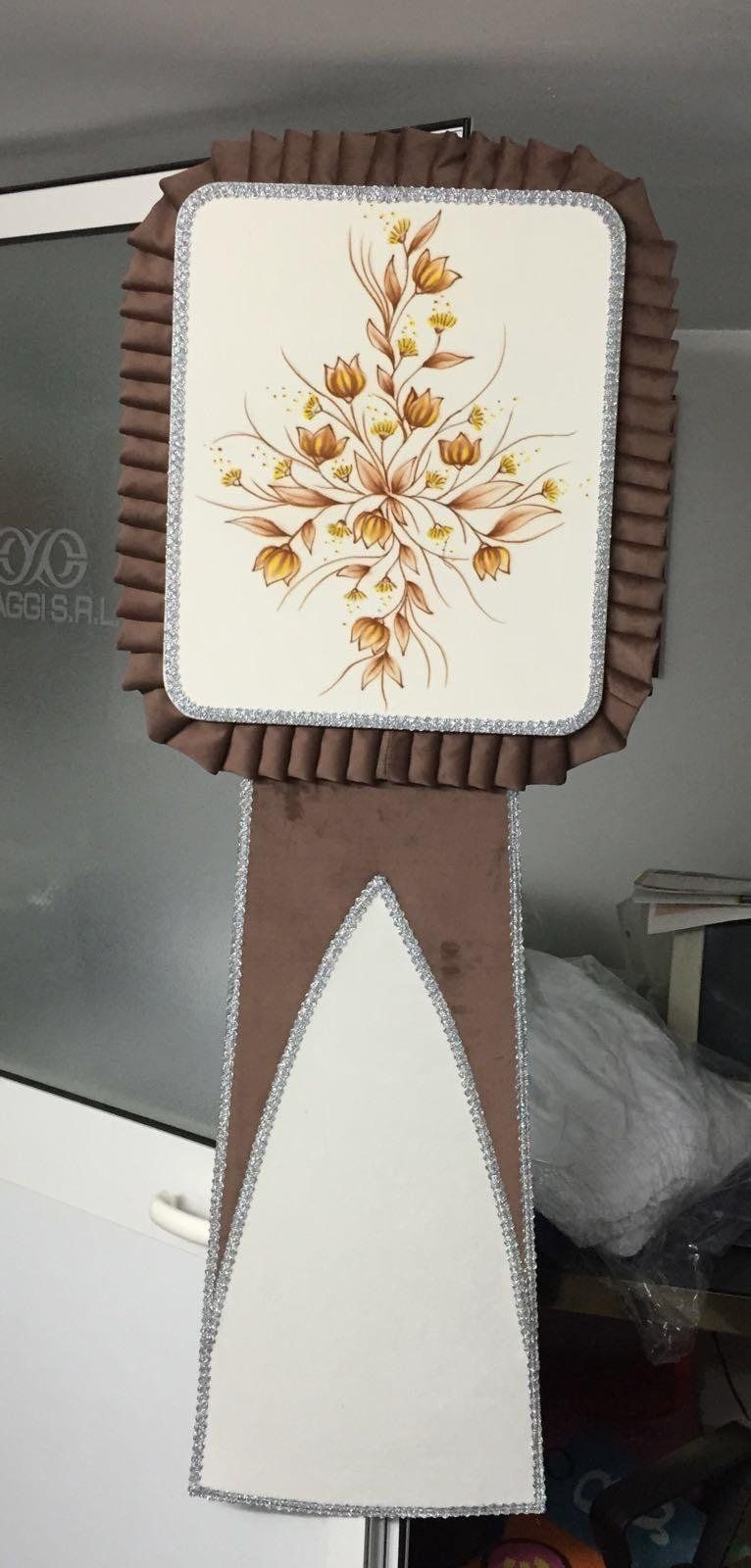 Opera d'arte floreale in tessuto marrone e crema. Ha una parte superiore rettangolare con volant marroni e una base lunga.