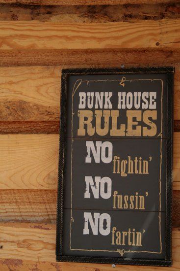 A sign on a wooden wall that says bunk house rules