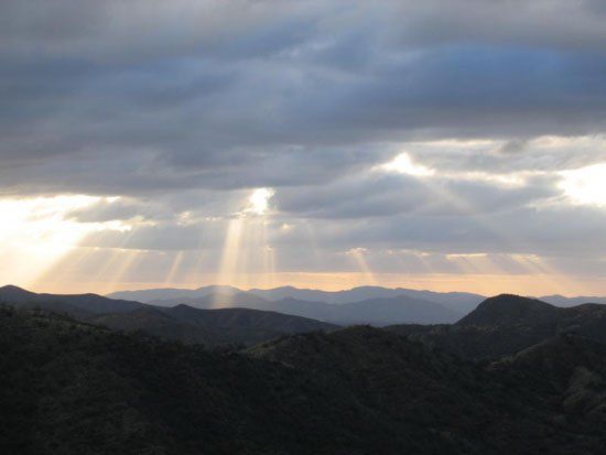 The sun is shining through the clouds over the mountains