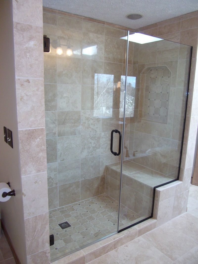 A bathroom with a glass shower door and a bench.