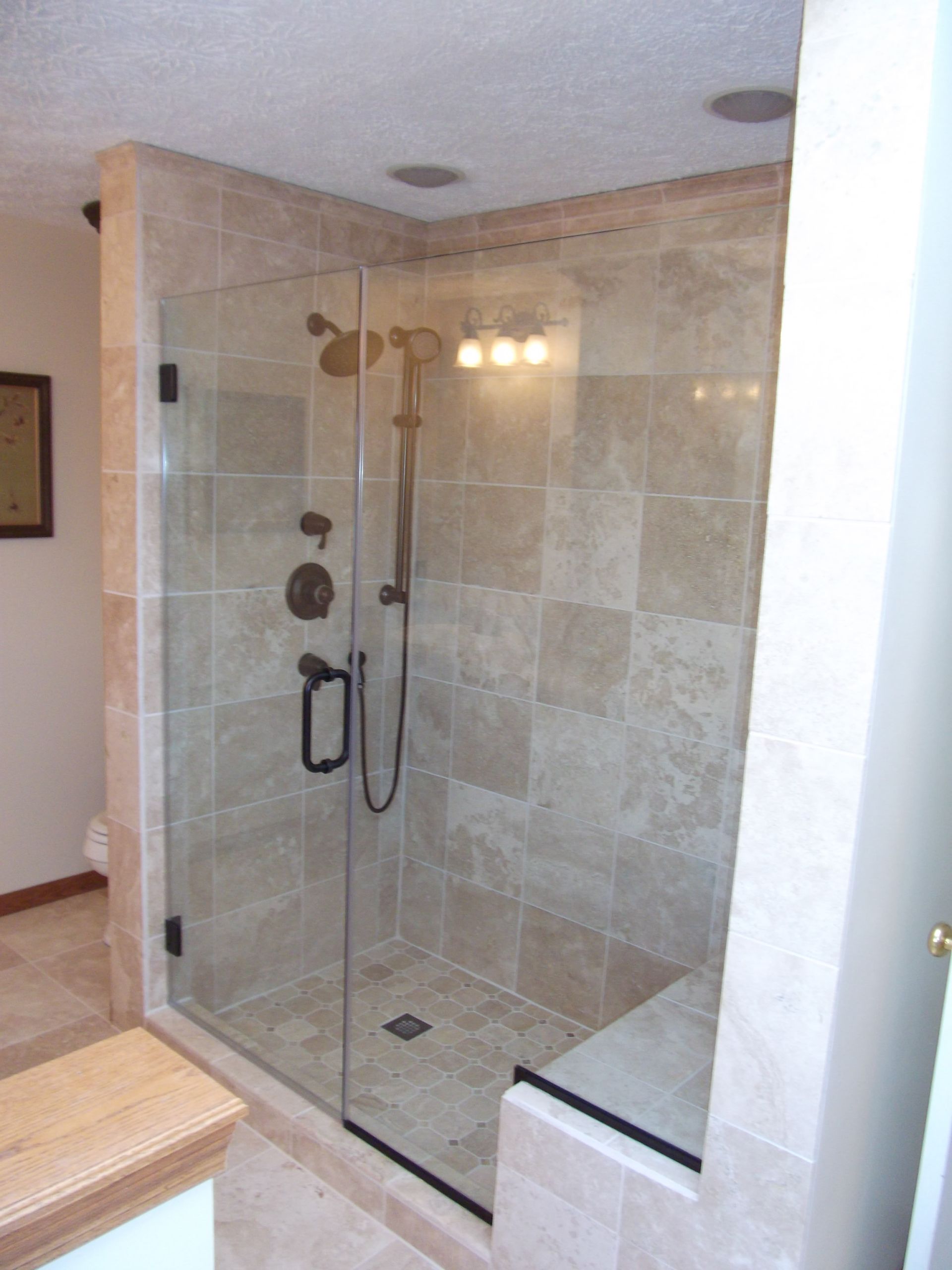 A bathroom with a walk-in shower and a glass door.