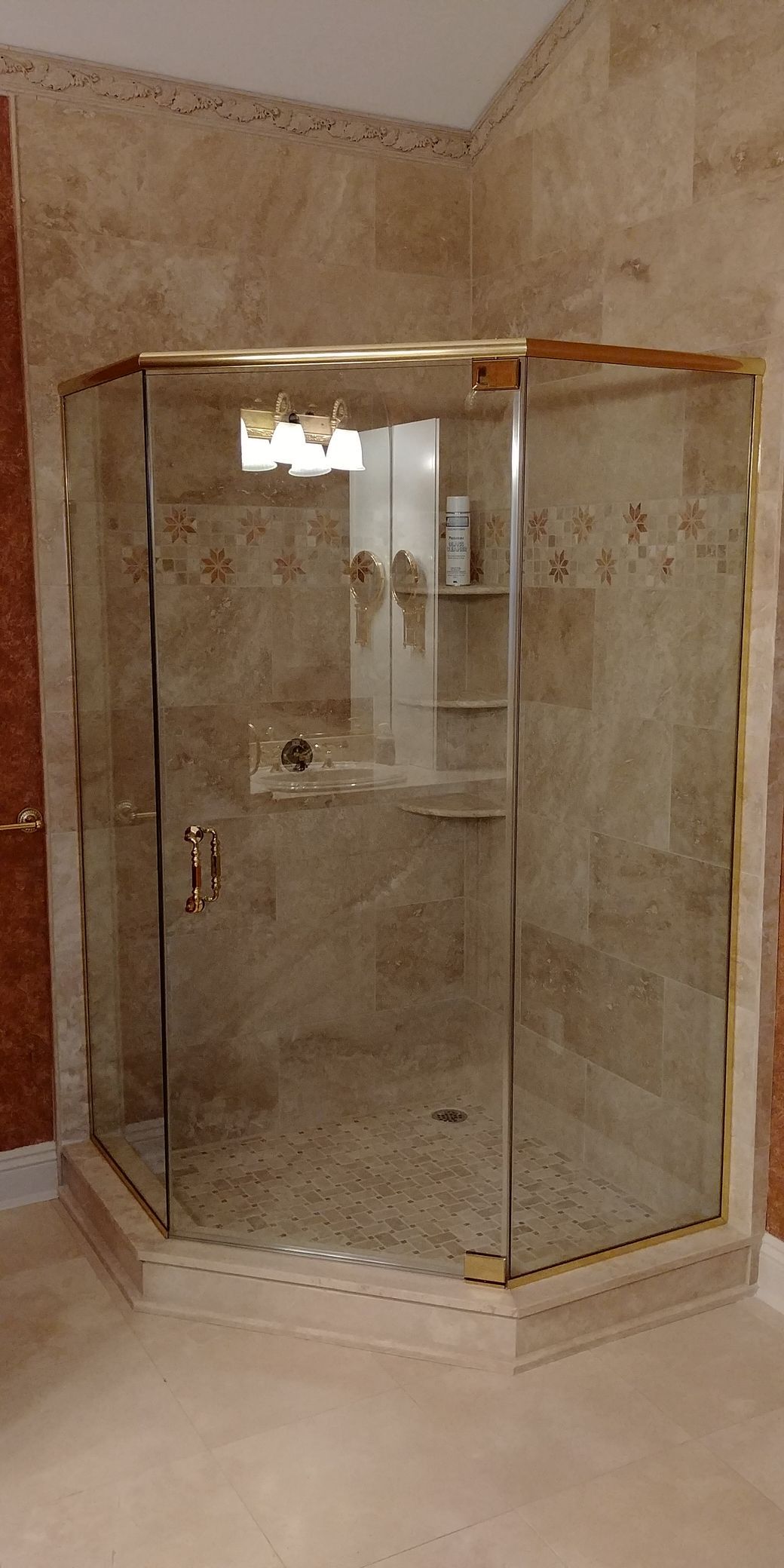 A bathroom with a walk in shower with a gold frame.