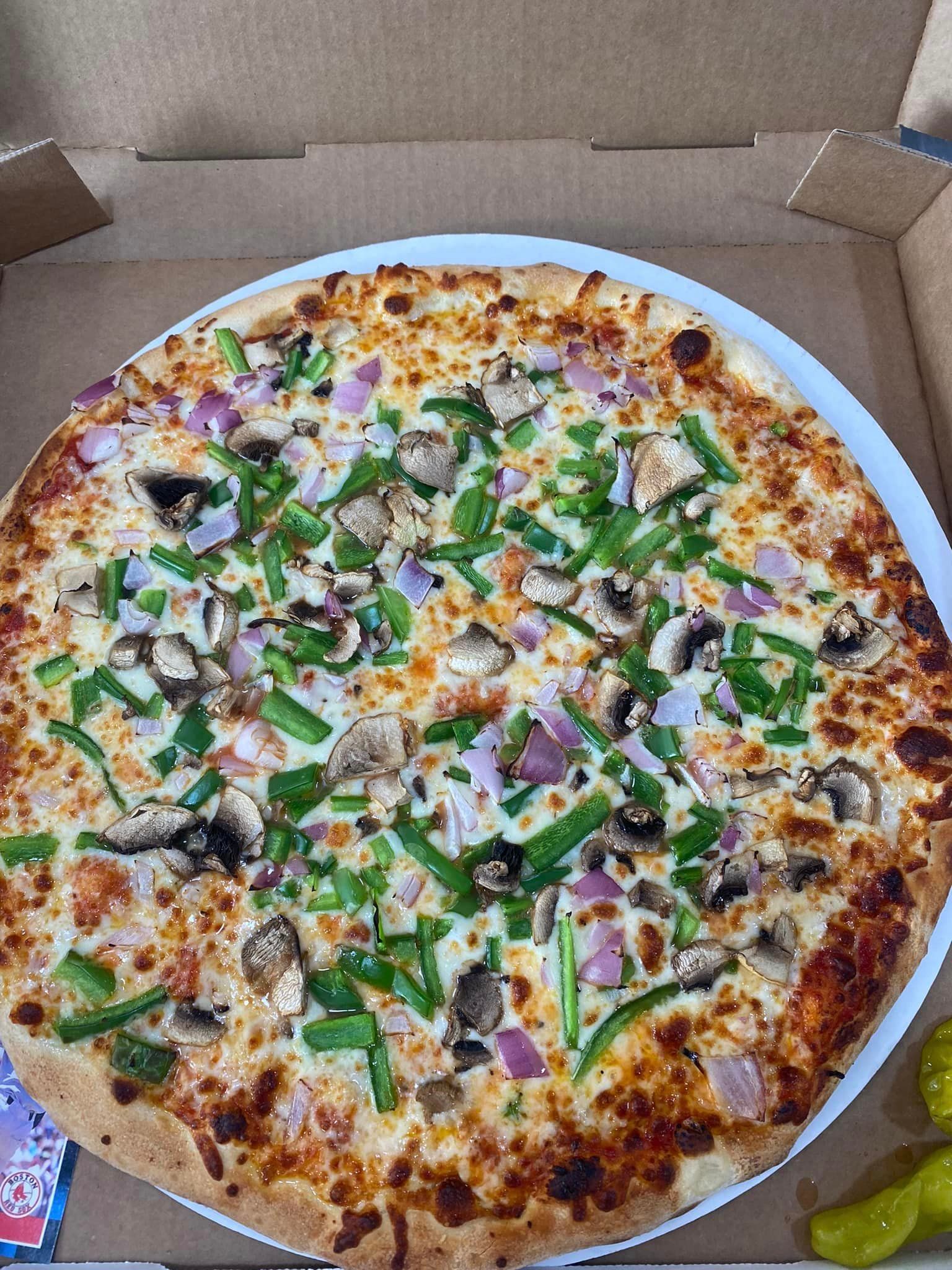 A pizza with mushrooms , green peppers , onions and cheese is in a box.