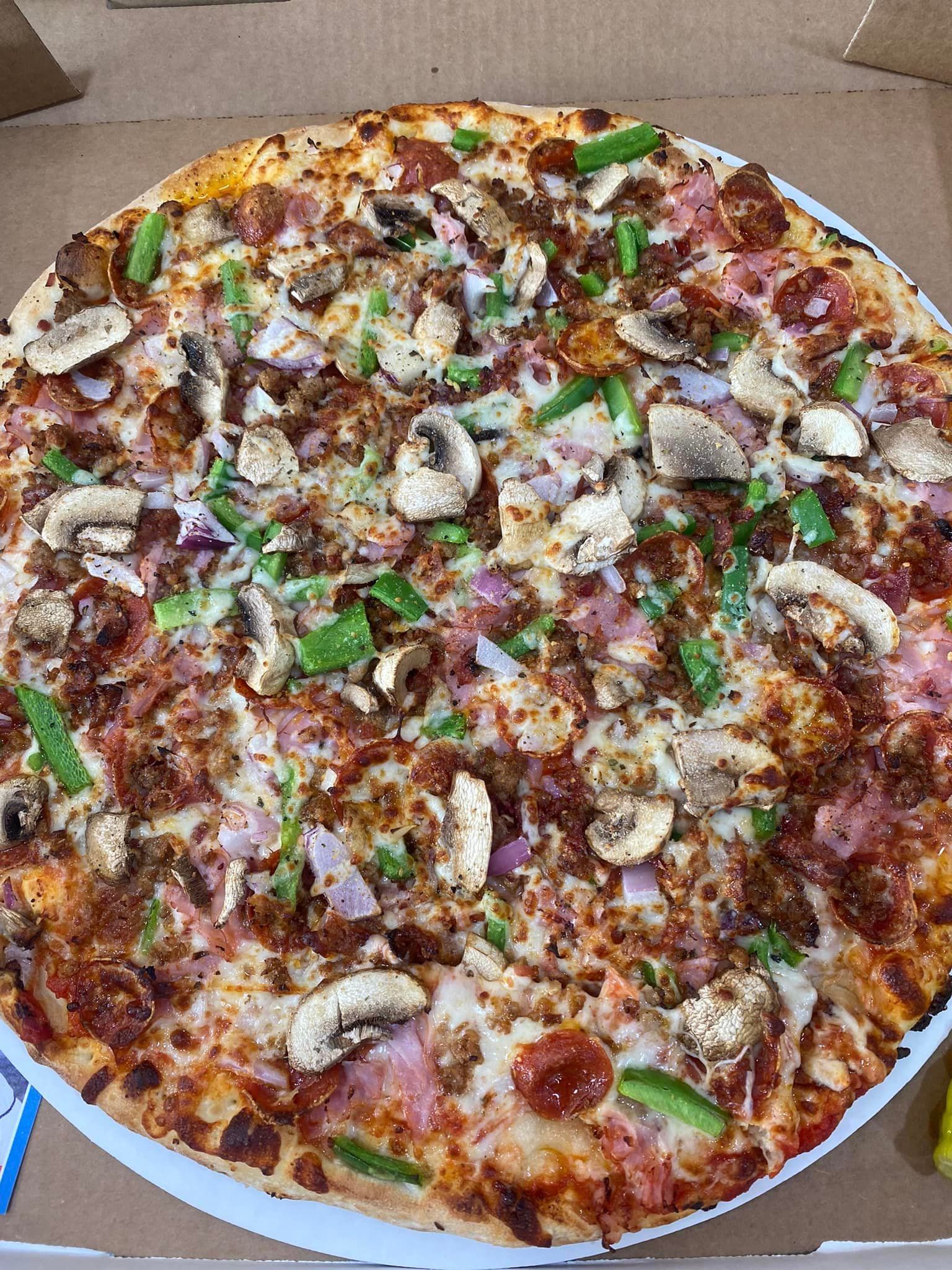 A pizza with a lot of toppings on it is in a box.