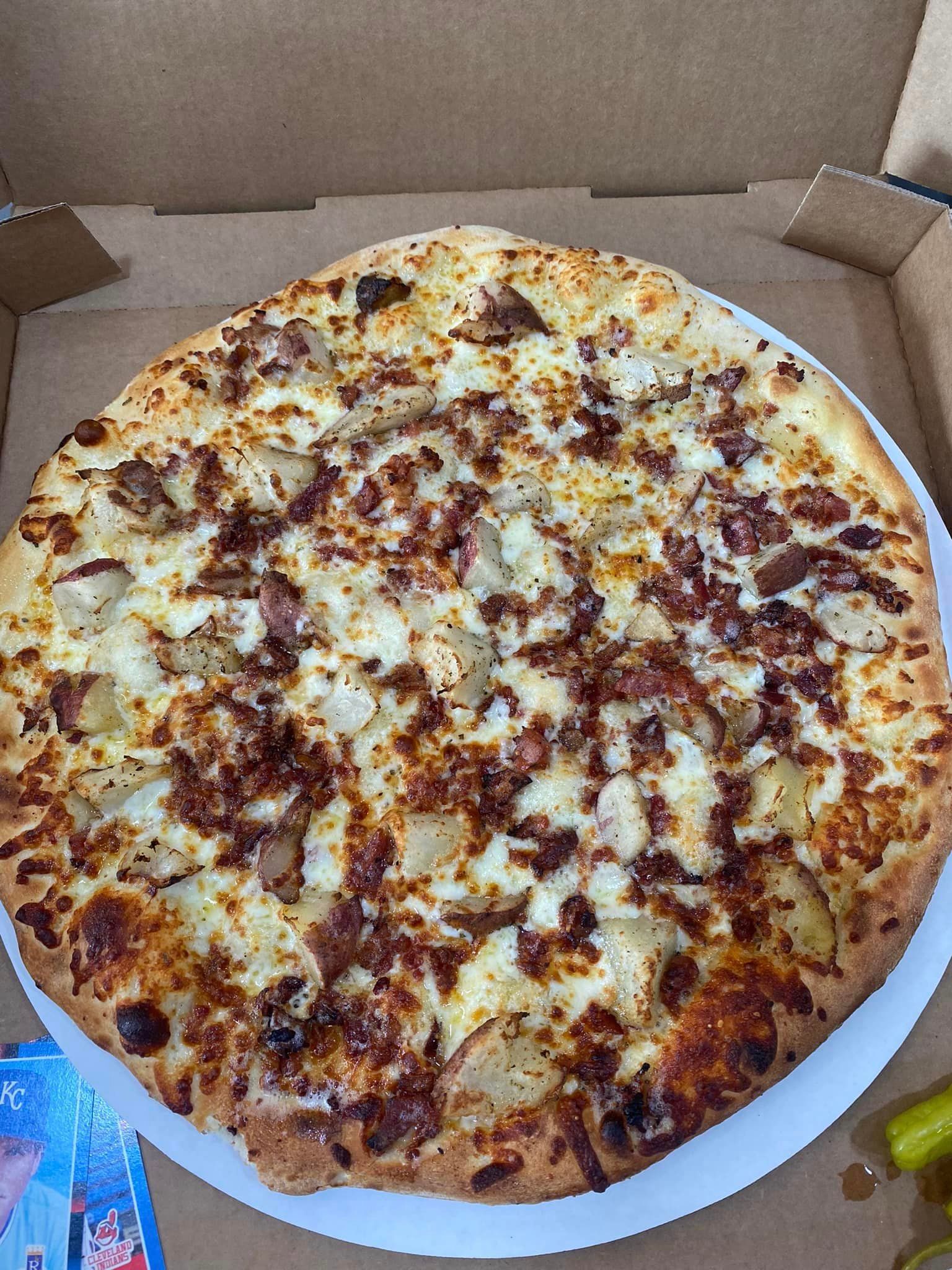 A pizza with mushrooms , green peppers , onions and cheese is in a box.
