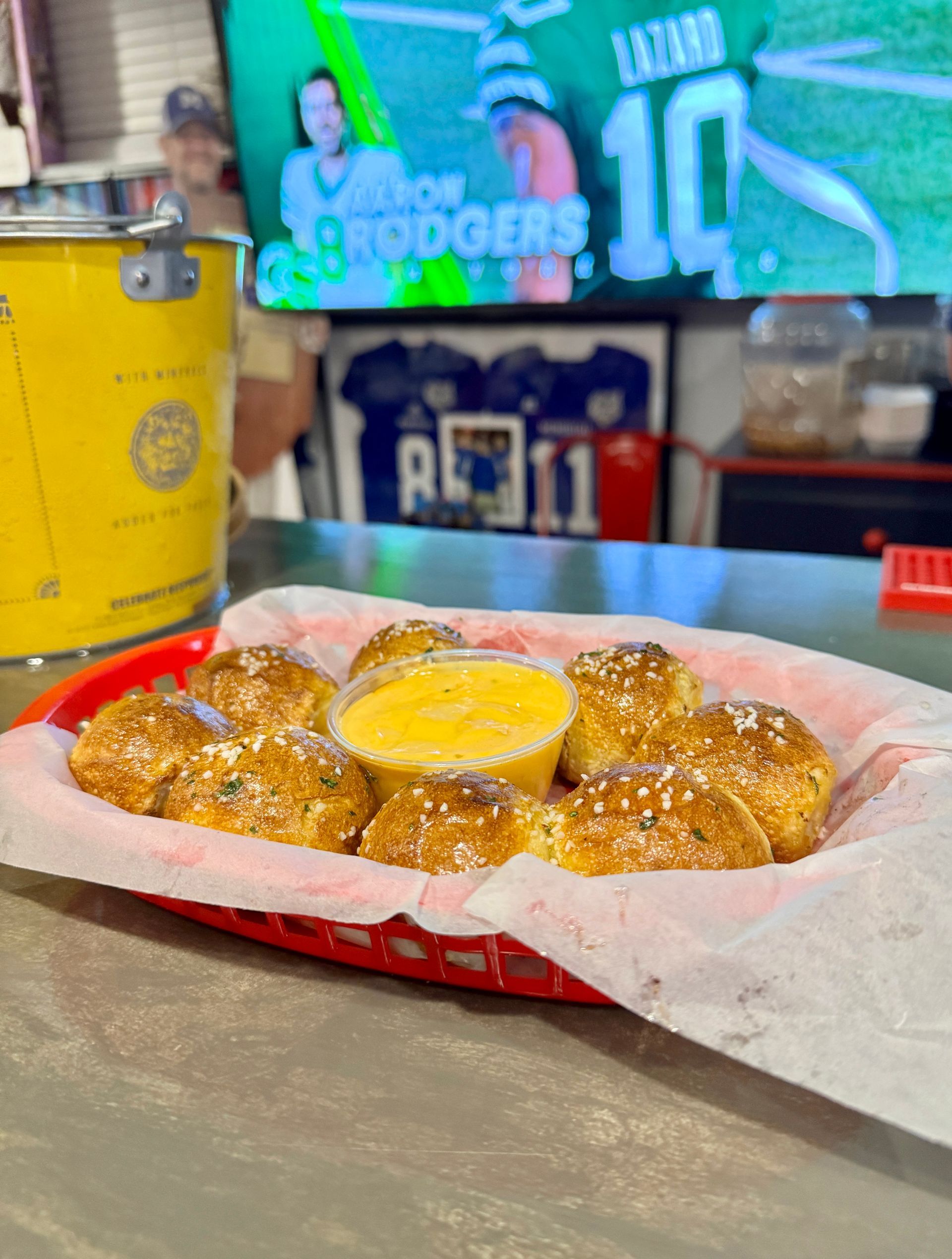 A basket of pretzel knots with cheese dipping sauce on a table.