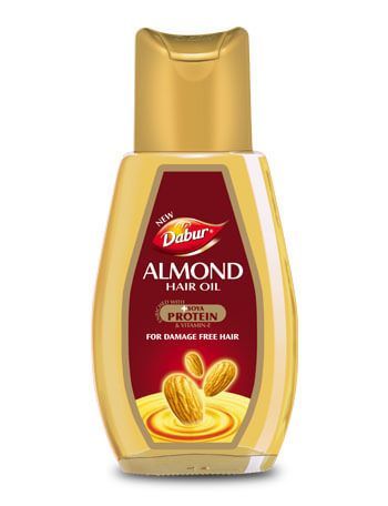 Gold bottle of Dabur Almond Hair Oil with almonds on the label, shown on a white background