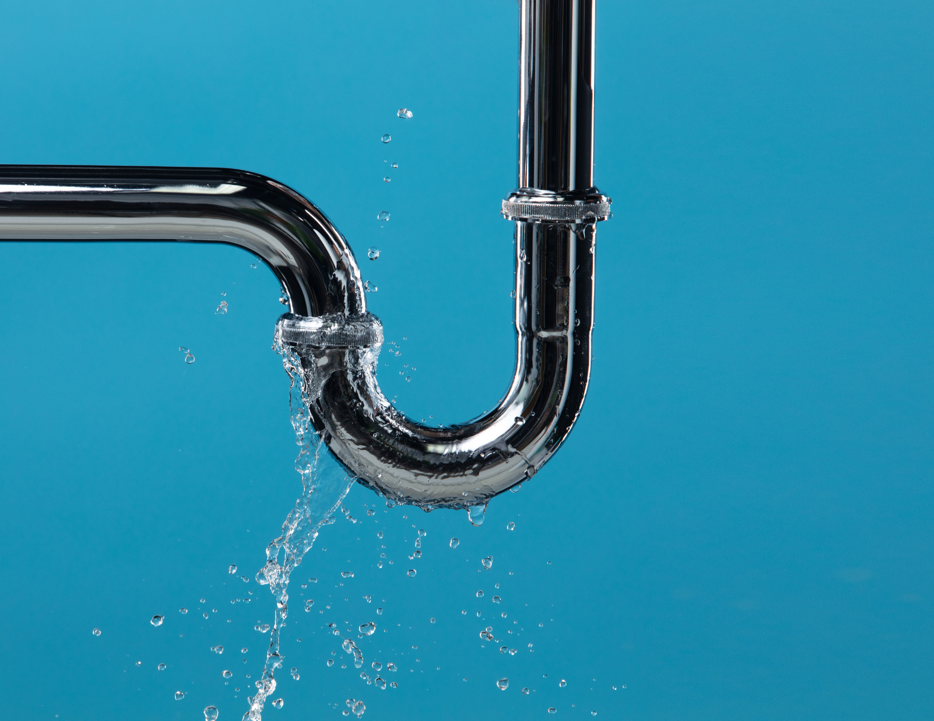 Leaking chrome pipe against a bright blue background with water splashing out