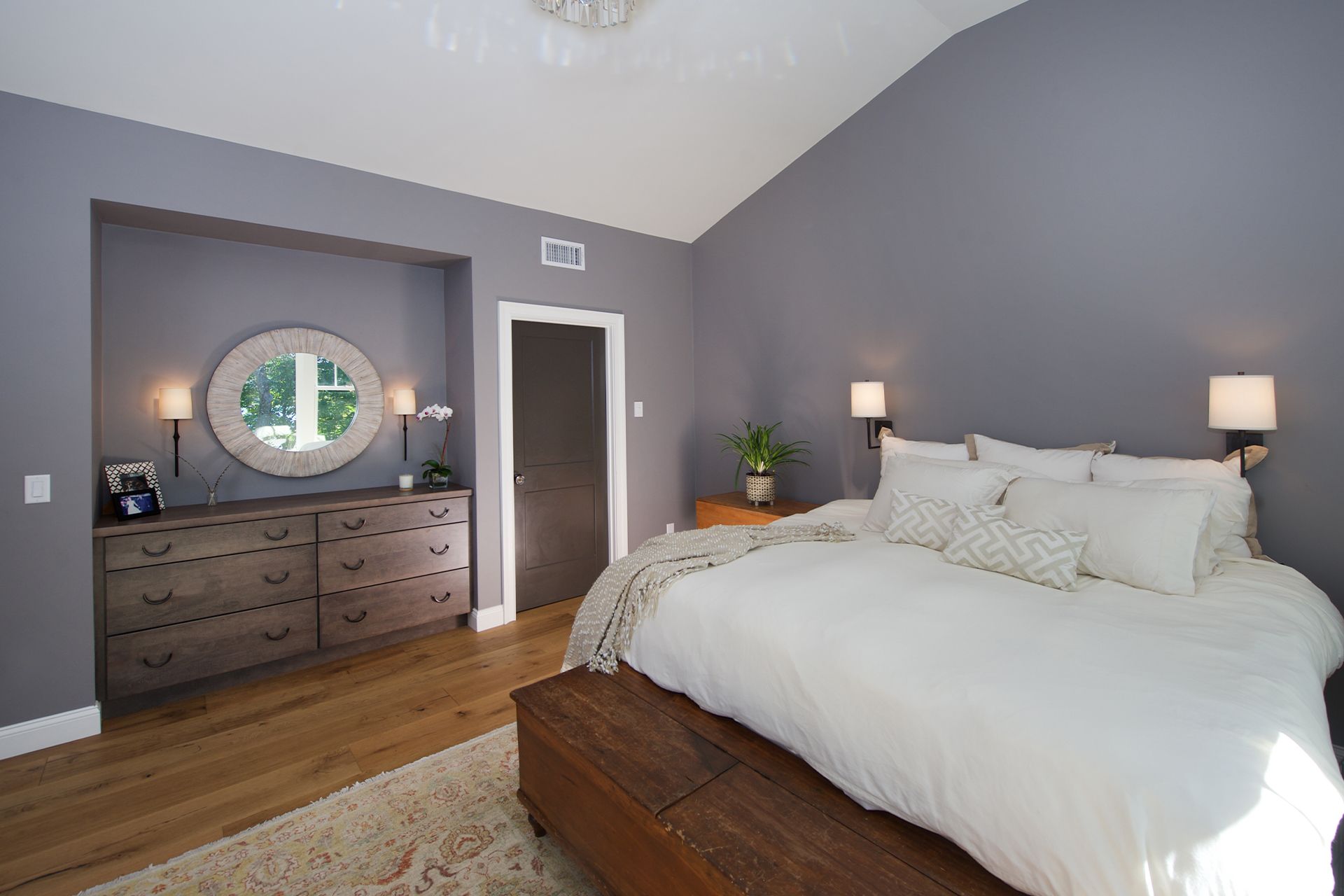 A bedroom with a bed , dresser , and mirror.