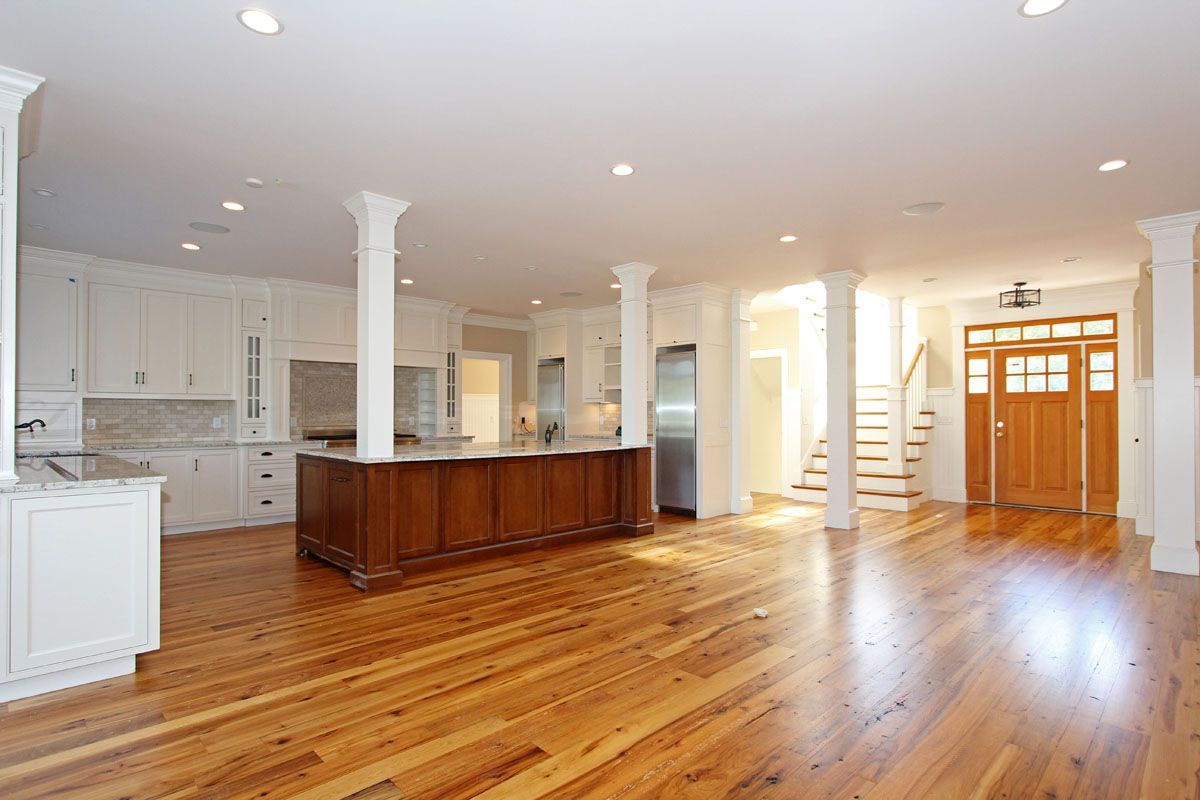 A large empty kitchen with wooden floors and white cabinets.