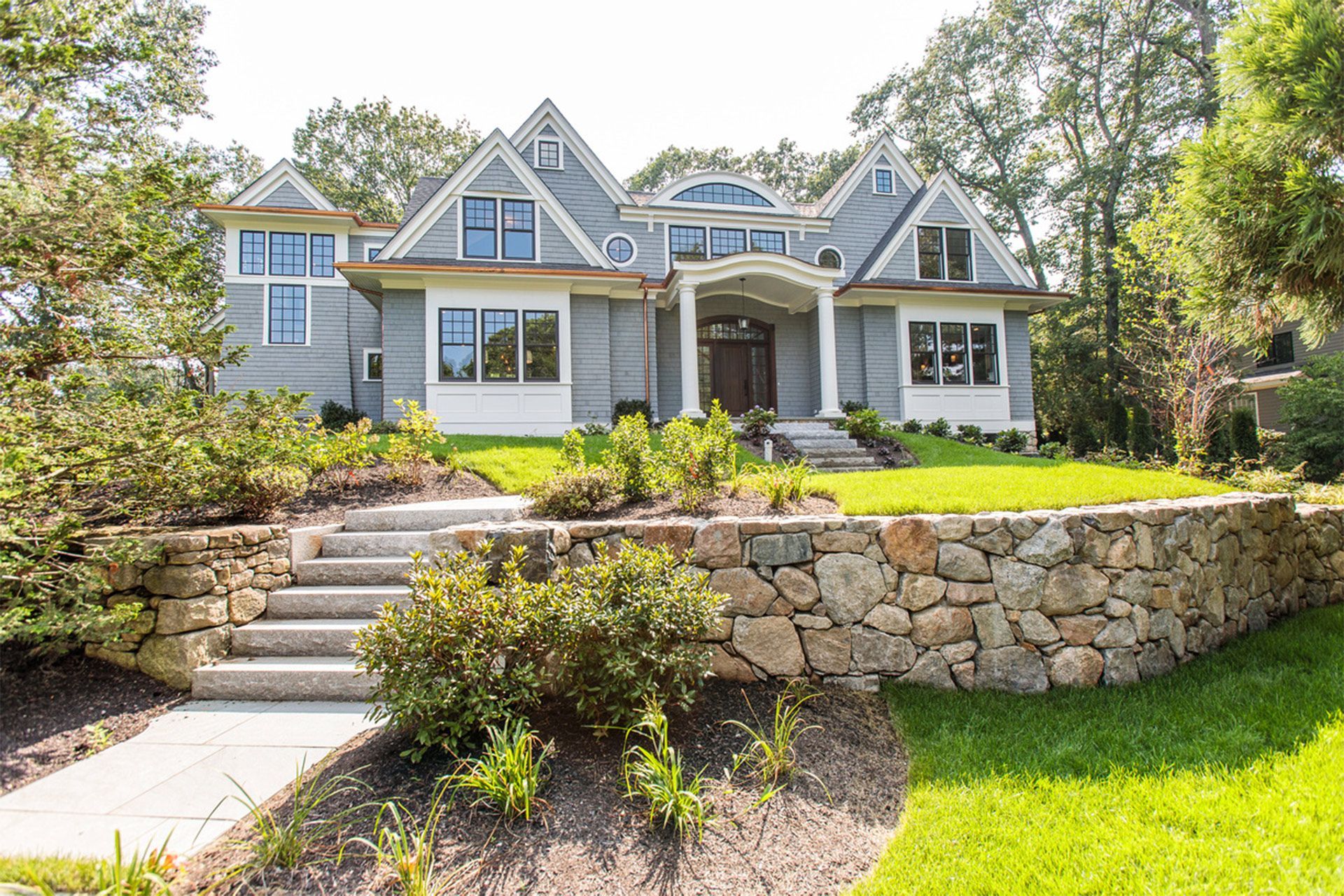 A large house with a stone wall in front of it.