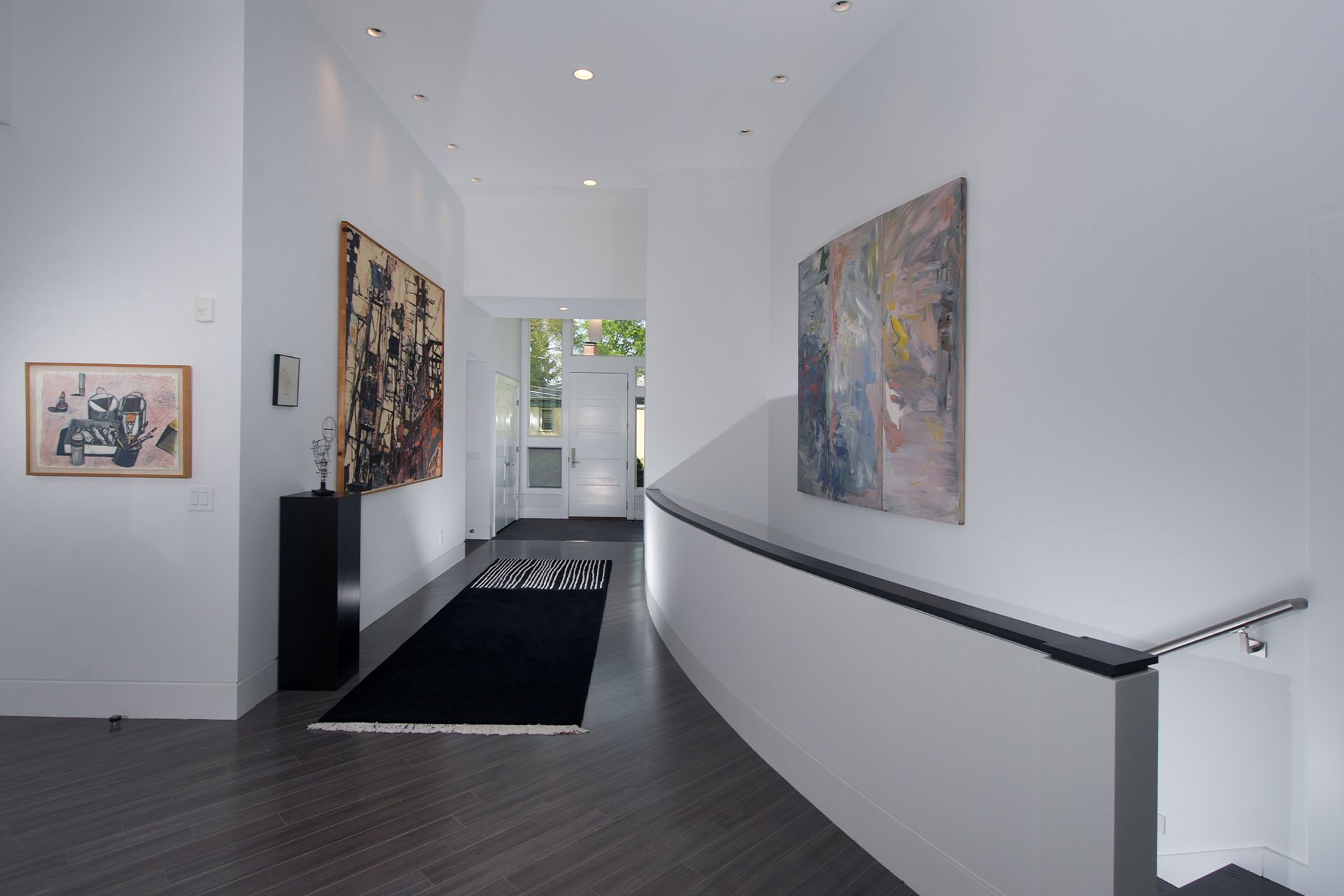 A hallway with a black rug and paintings on the wall