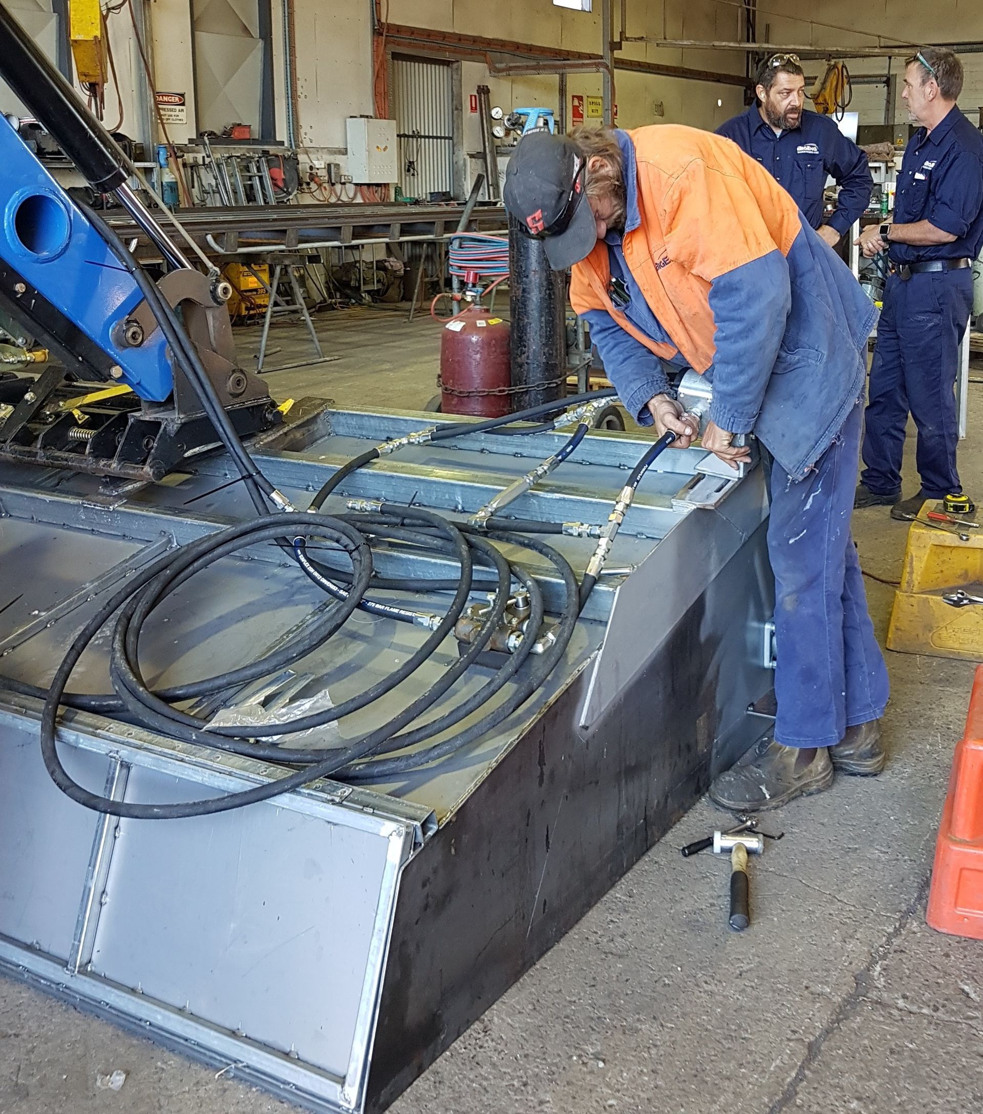 A man in an orange vest is working on a machine