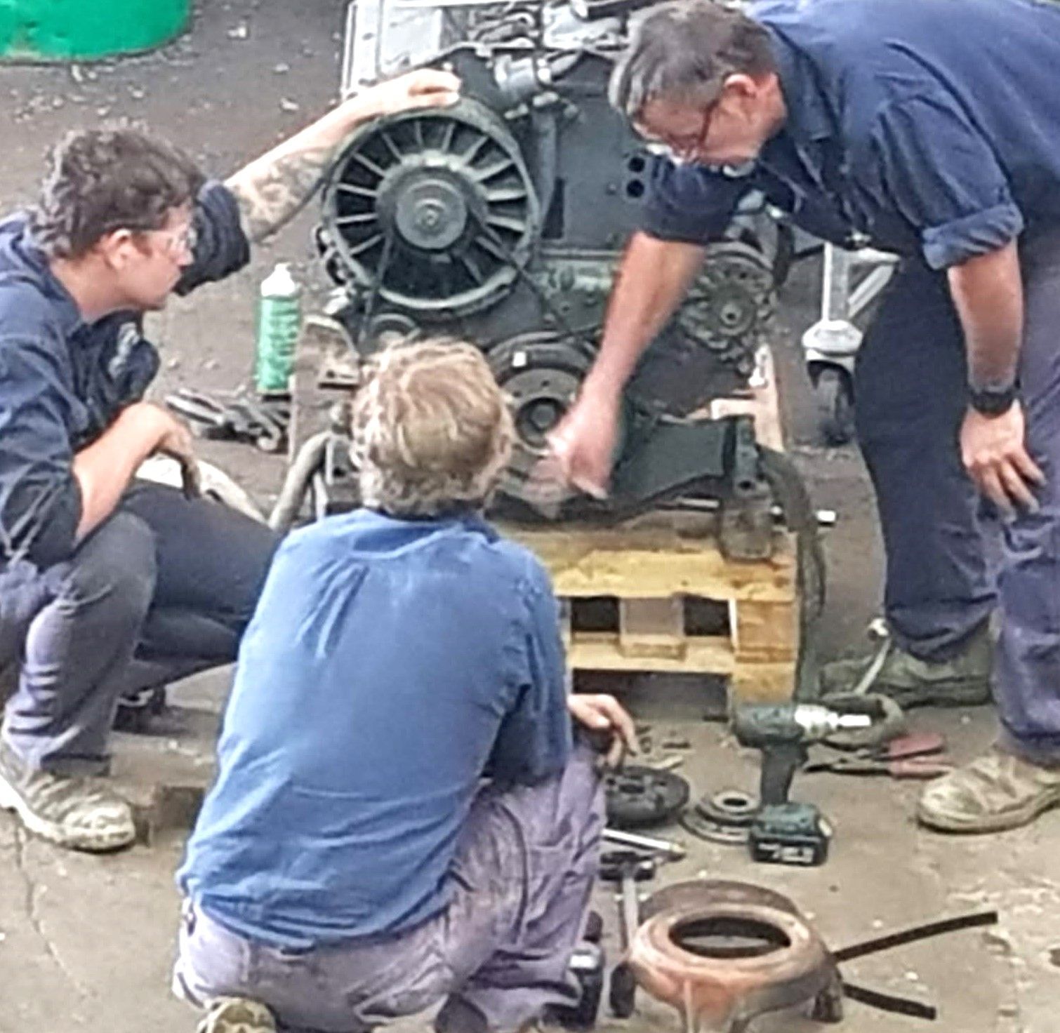 A group of men are working on a machine in a garage.