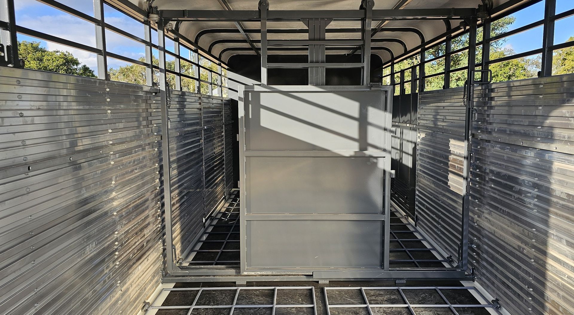 The inside of a horse trailer with a fence and a door.