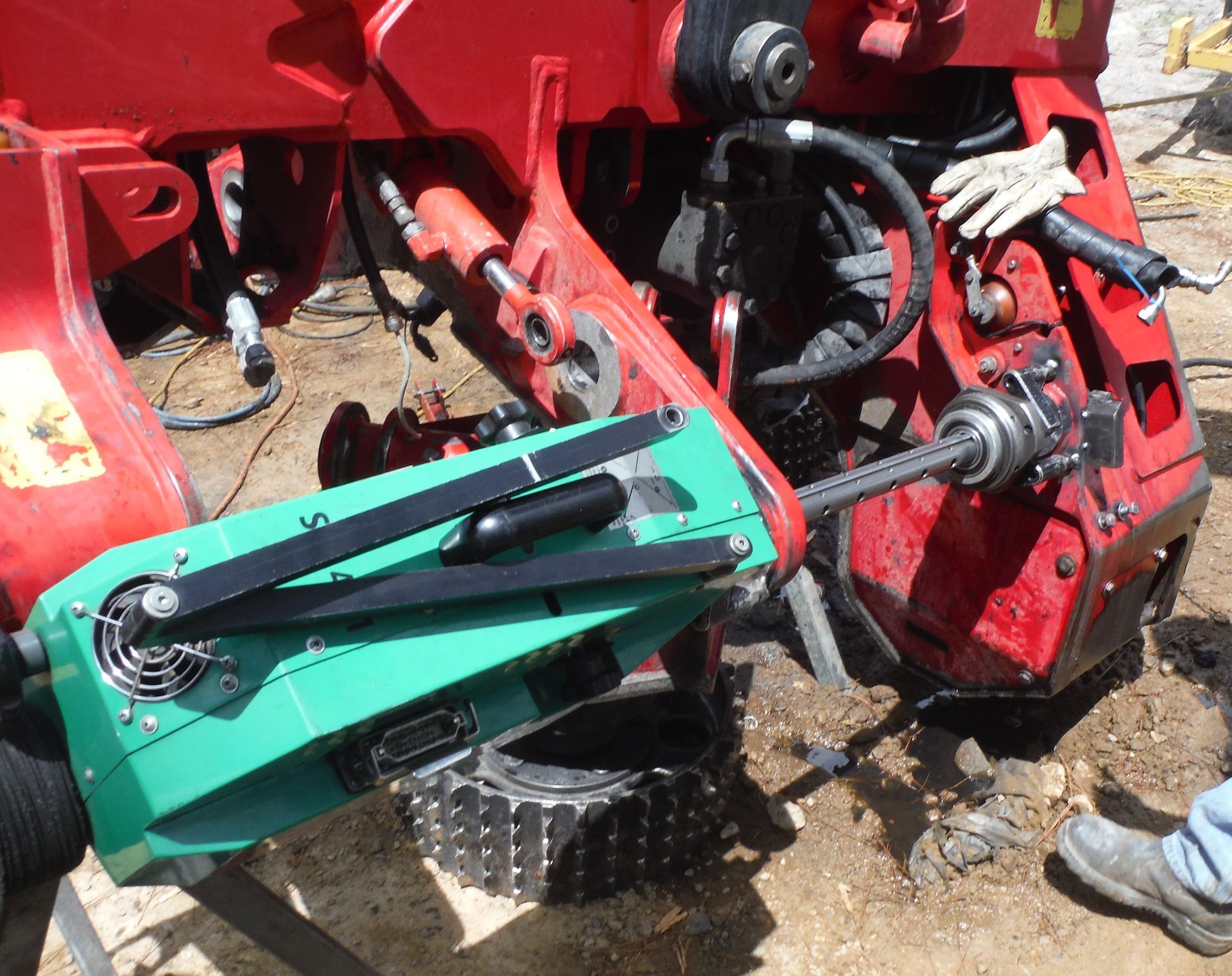 A red tractor with a green tool attached to it