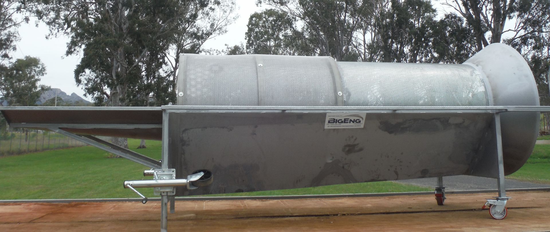 A large stainless steel container with a few trees in the background