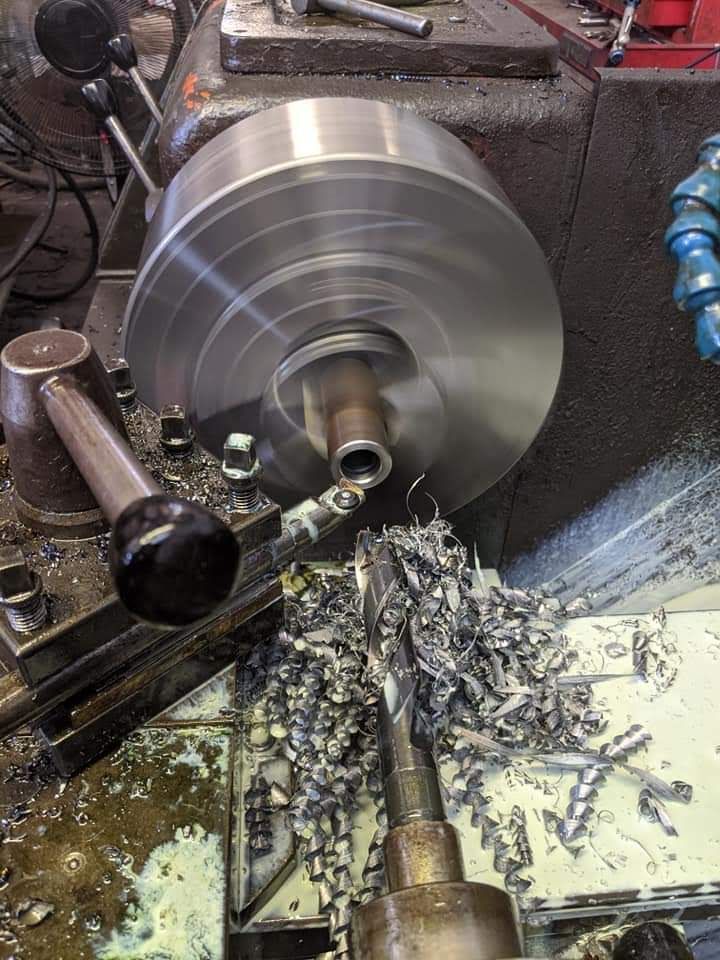 A machine is cutting a piece of metal on a lathe.