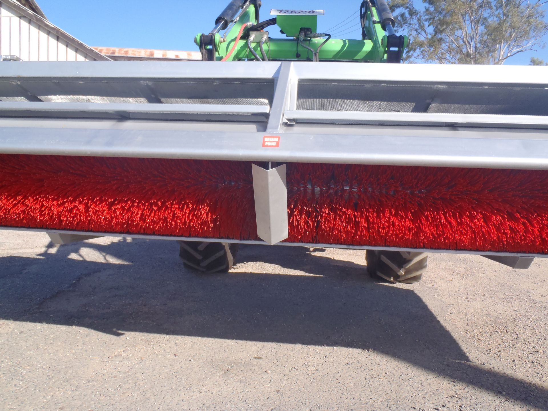 A tractor with a red brush attached to it