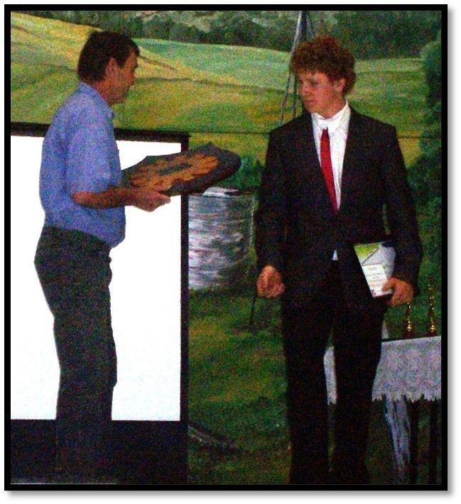 A man in a suit and tie is giving another man a painting