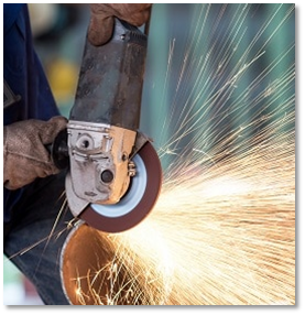 A person is grinding a metal pipe with sparks coming out of it