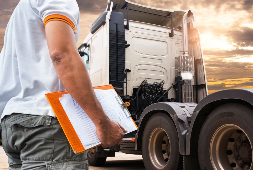 A Man is Holding a Clipboard in Front of a Semi Truck — Ceely's Heavy Vehicle Driver Training & Assessments In Albury, NSW