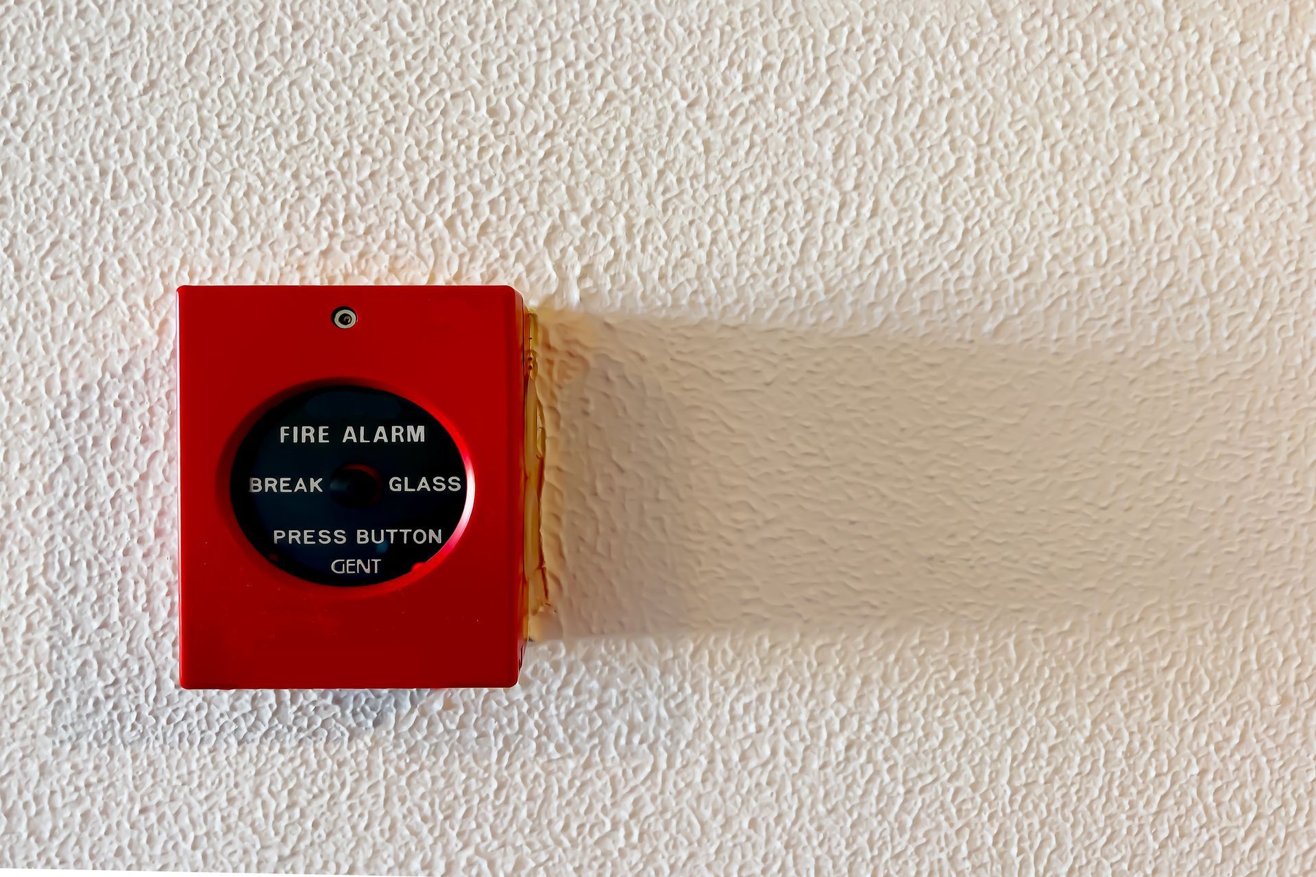 A person is pressing a button on a fire alarm.