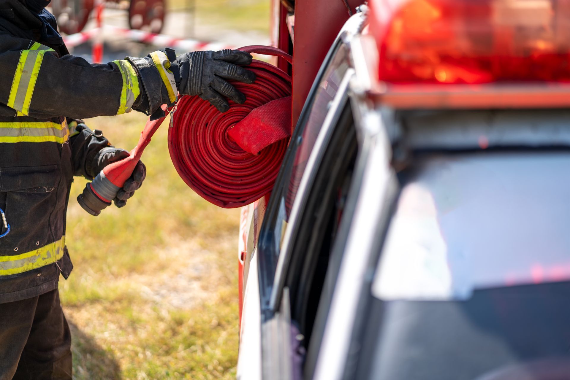 A fireman is holding a hose in front of a fire truck.