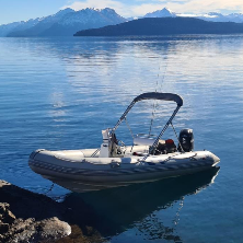 Un barco flota sobre un lago con montañas al fondo.