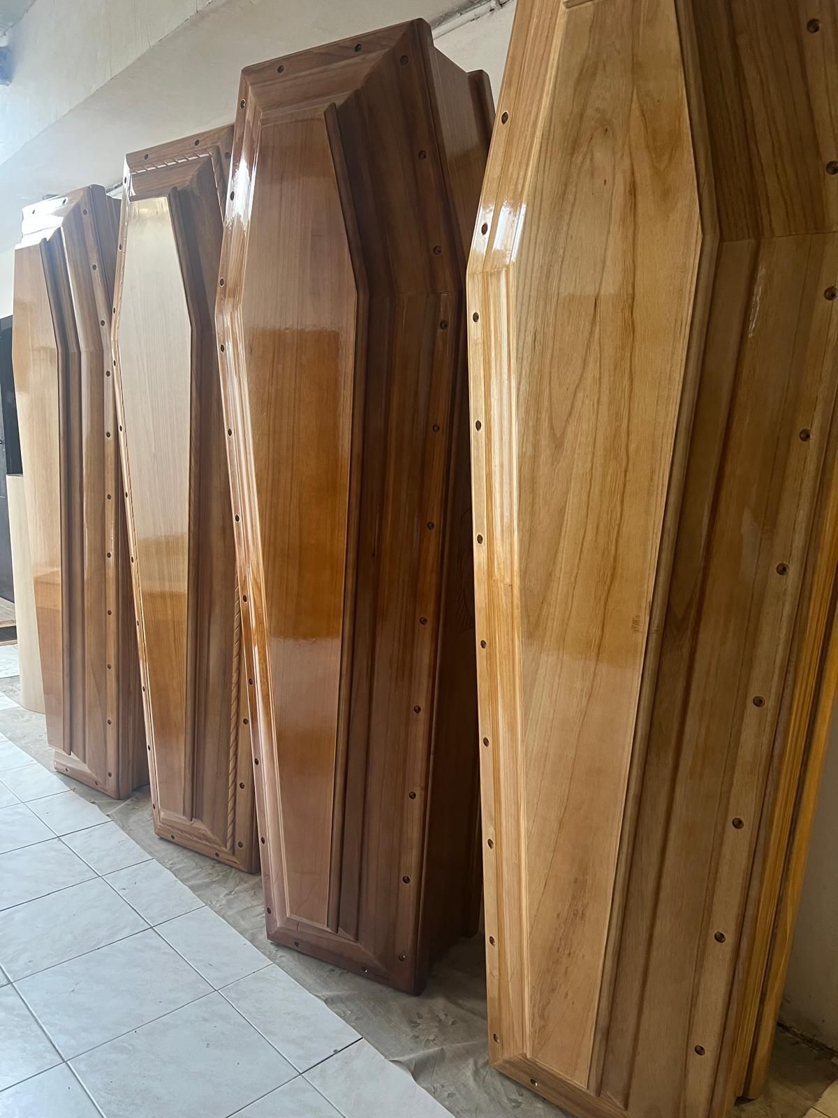 Cinque bare di legno lucidato allineate contro un muro.