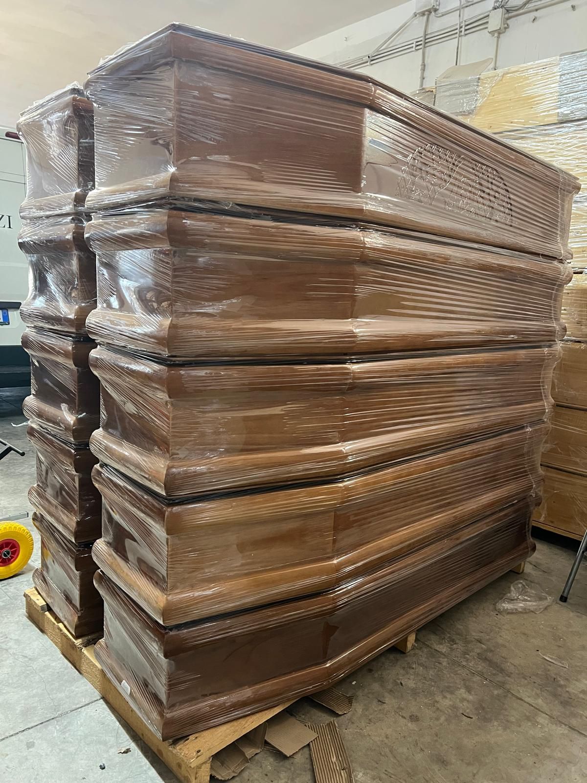 Bare marroni impilate e avvolte nella plastica su un pallet di legno in un'area di stoccaggio.