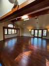 A bright, open room with polished wood floors, high vaulted ceilings with exposed wood beams, and large windows. A bright, open room with polished wood floors, high vaulted ceilings with exposed wood beams, and large windows.
