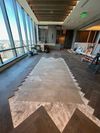 An interior construction space with unfinished herringbone wood flooring around a central, bare subfloor area. An interior construction space with unfinished herringbone wood flooring around a central, bare subfloor area.