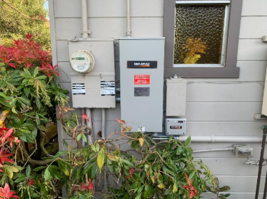 An electrical box on the side of a house next to a window.