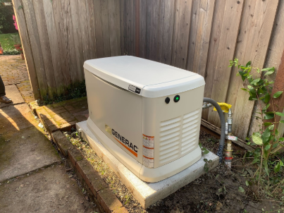 A generator is sitting in the dirt next to a wooden fence.