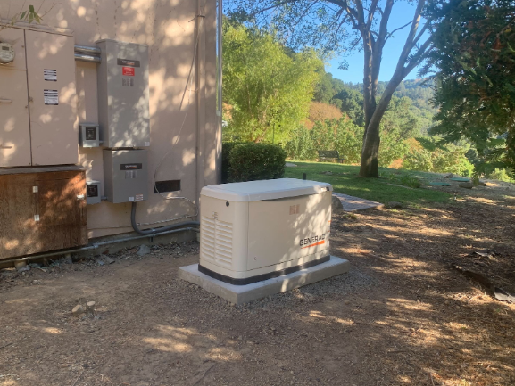 A generator is sitting in the backyard of a house.