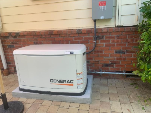 A generator is sitting on the side of a brick building.