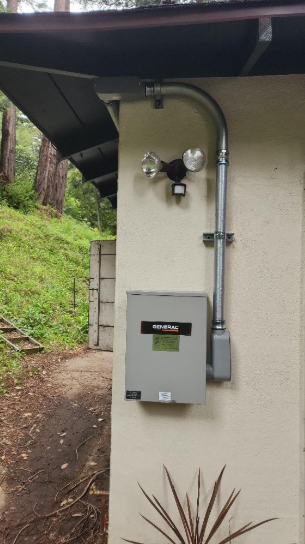 A box with a light attached to it is on the side of a building.