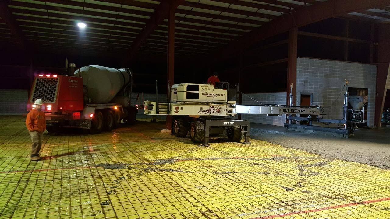 Truck and utility vehicle parked inside a lit industrial warehouse at night
