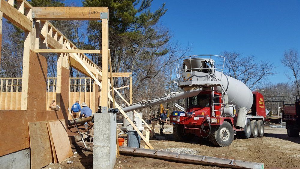 Construction site with a cement mixer truck pouring concrete into wooden house framing