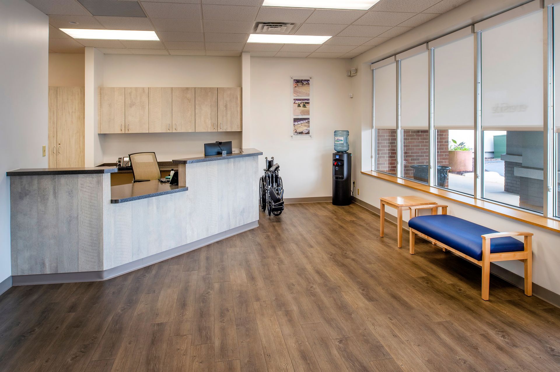 A waiting room with a desk , chairs , and a bench.