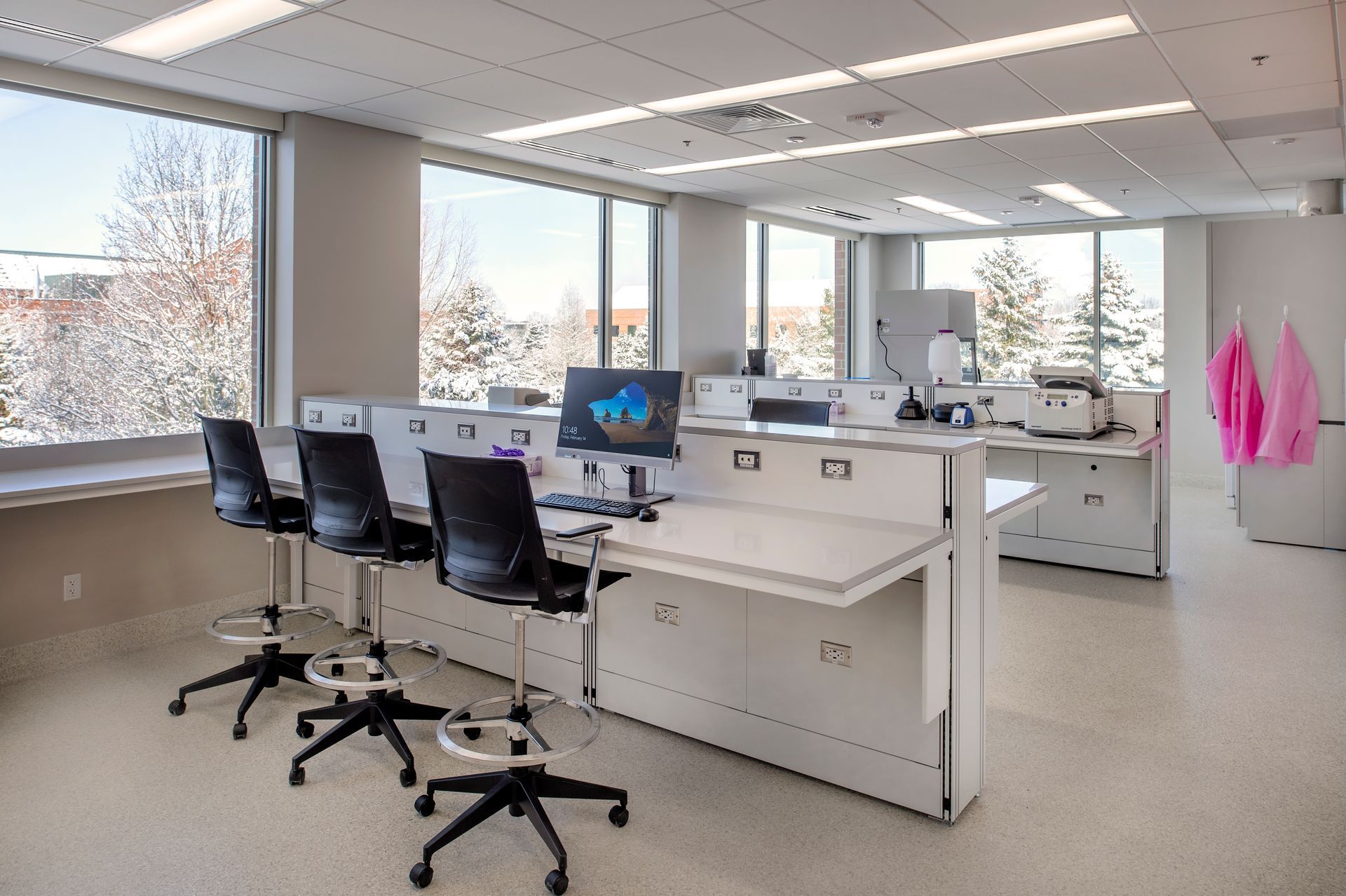 A room with a lot of windows and a desk with a computer on it