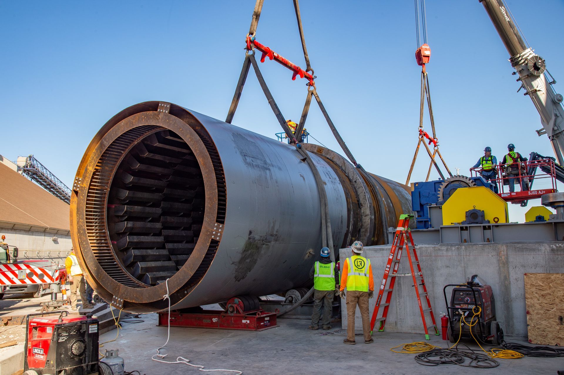 A large pipe is being lifted by a crane at a construction site.