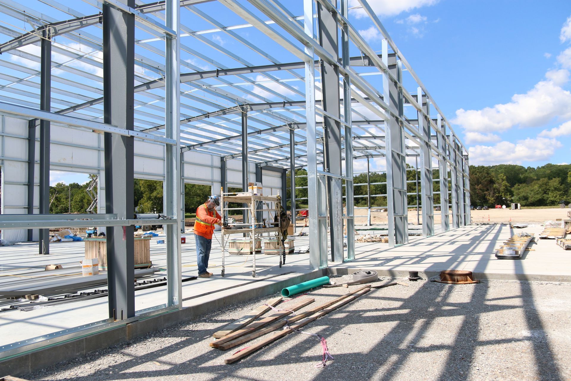 A man is standing in front of a large metal structure under construction.