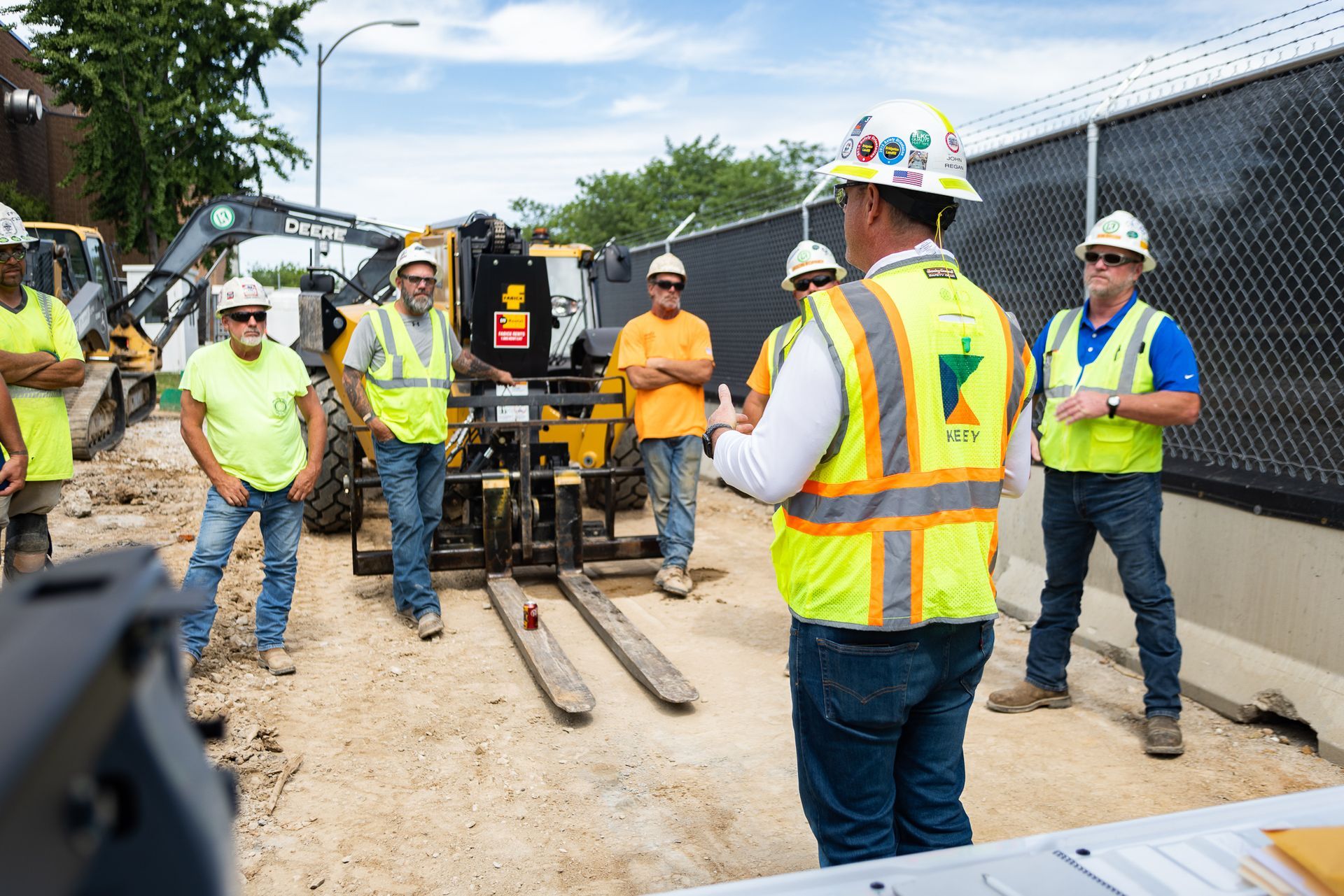 A group of construction workers are standing around a forklift on a construction site.