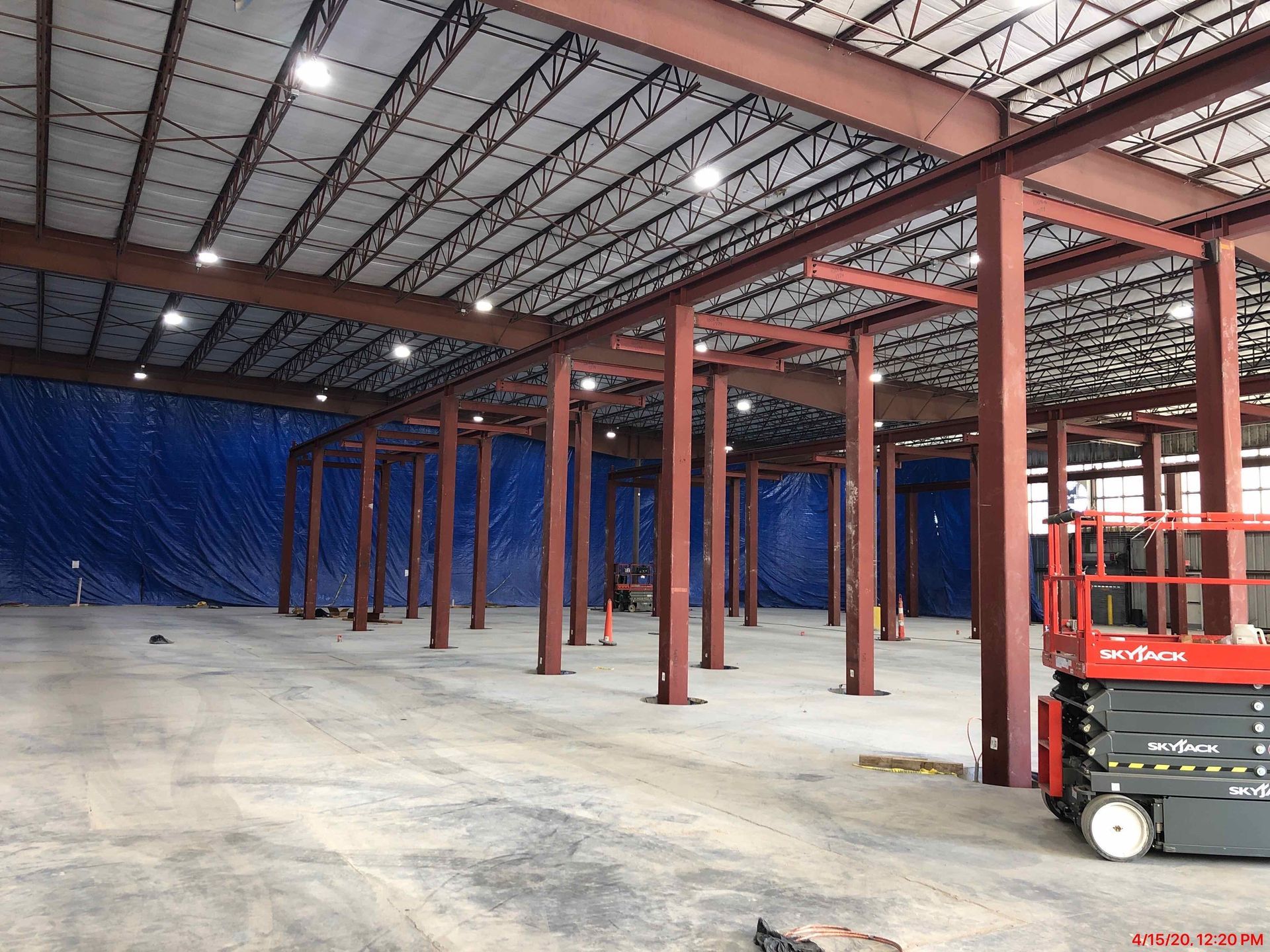 A red scissor lift is parked in the middle of a large warehouse.