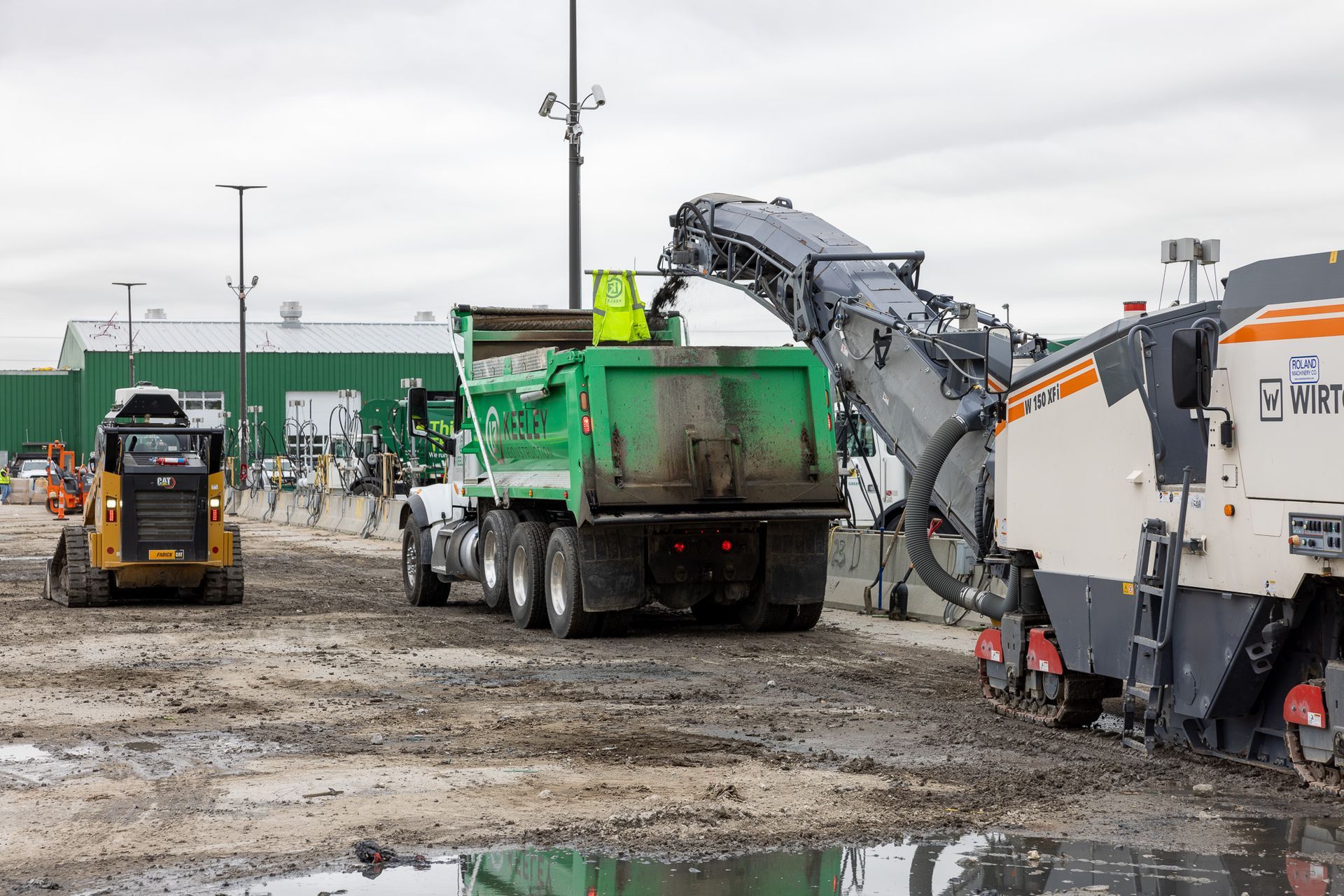 A dump truck is being loaded with dirt by a machine.